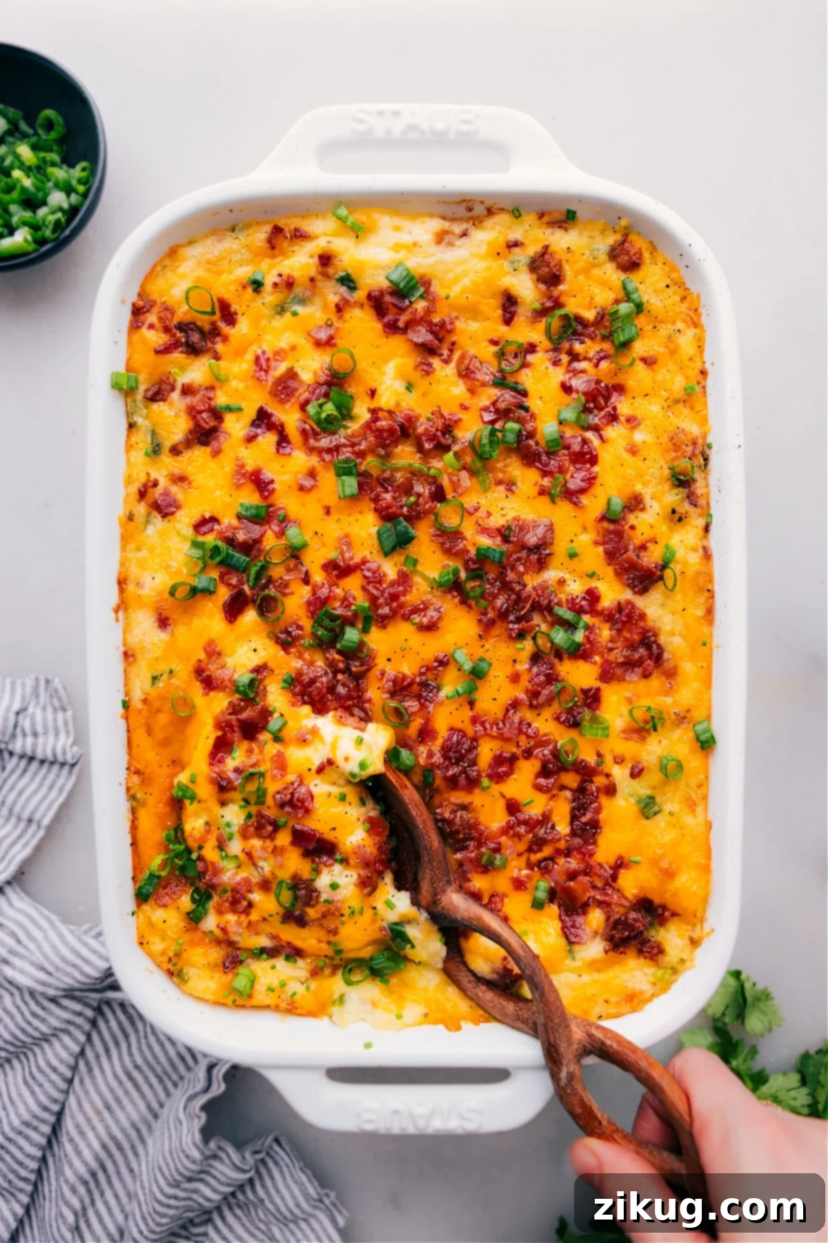 Twice-Baked Potato Casserole: A cheesy and comforting dish for any gathering Twice-Baked Potato Casserole in a baking dish, garnished with fresh herbs and ready to serve.