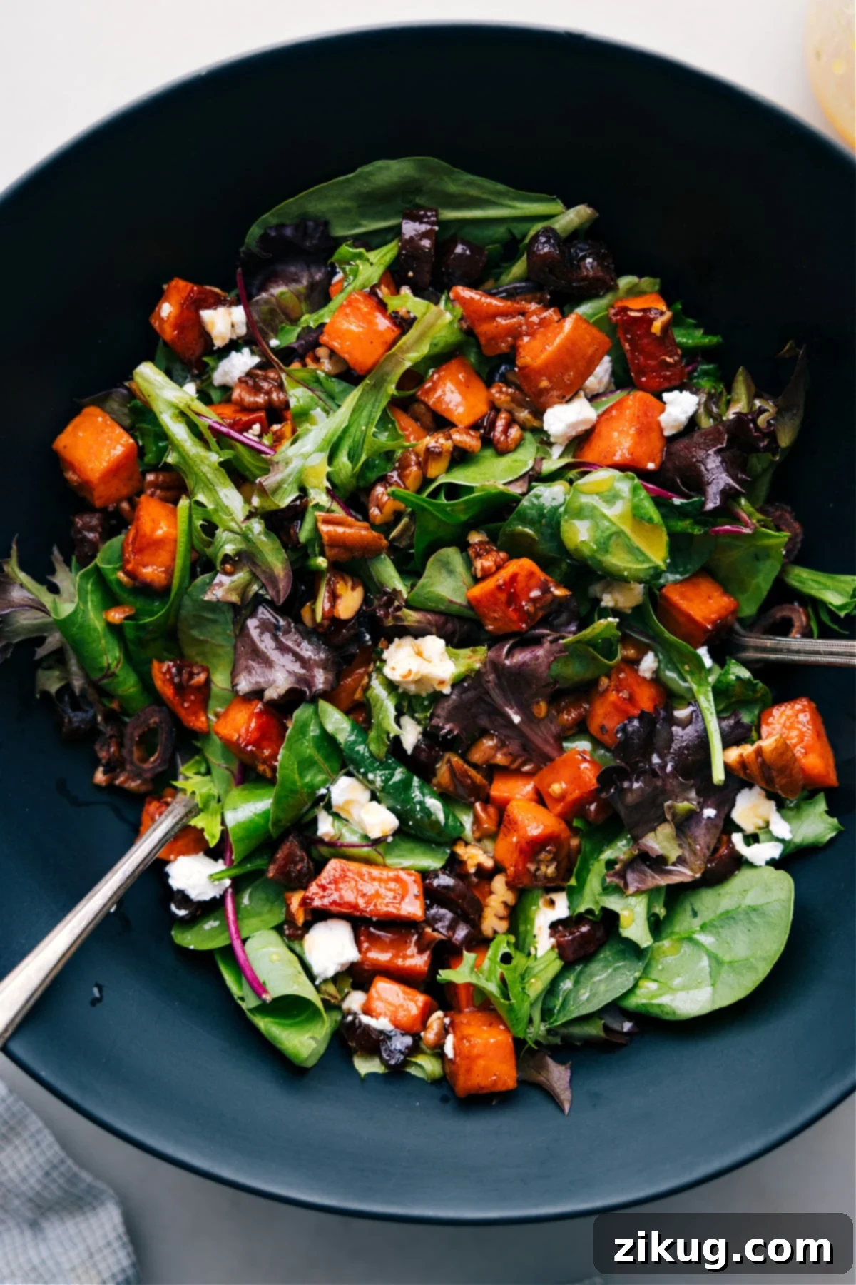 Colorful and Flavorful: Dive into This Delicious Sweet Potato Salad! A vibrant bowl of sweet potato salad, featuring diced roasted sweet potatoes mixed with various colorful ingredients and a creamy dressing.