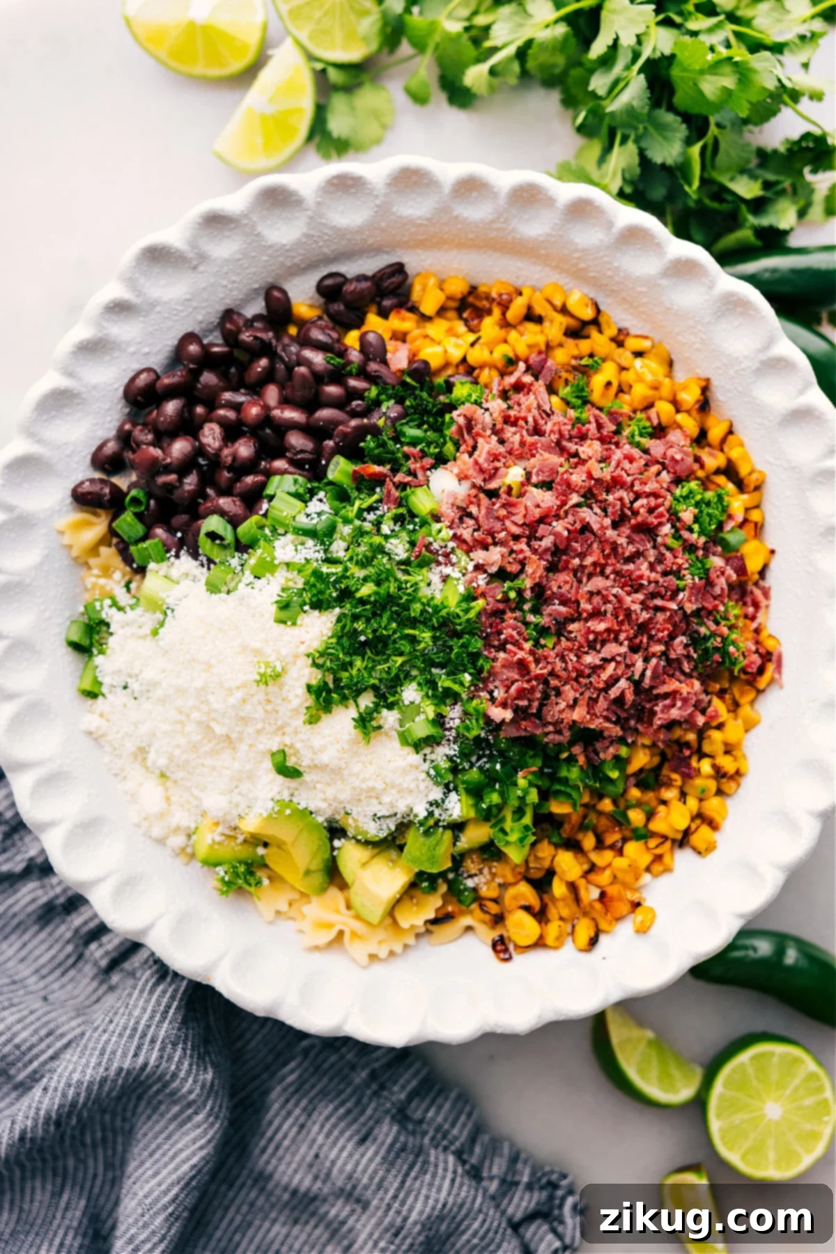 Assembling the Best Mexican Street Corn Pasta Salad A large mixing bowl filled with all the prepared ingredients for Mexican Street Corn Pasta Salad: cooked pasta, charred corn, diced avocado, black beans, fresh herbs, crispy bacon, and Cotija cheese, ready to be tossed with the creamy dressing.