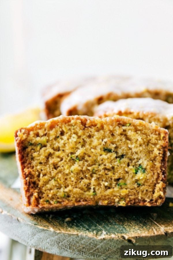 A perfectly baked slice of moist lemon zucchini bread, adorned with a sweet and tangy glaze, ready to be served.