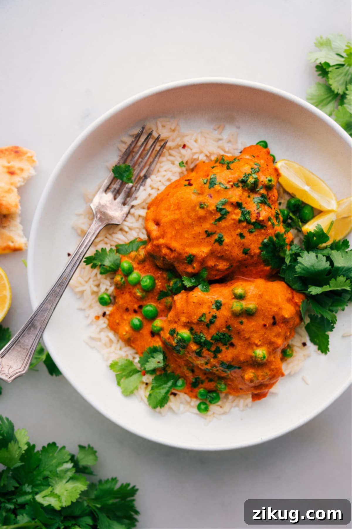 Exquisite and Aromatic Chicken Tikka Masala Served Over Fluffy Rice A perfectly plated dish of Chicken Tikka Masala, featuring tender chicken in a rich, creamy sauce, served atop a bed of fragrant basmati rice, garnished with fresh cilantro.