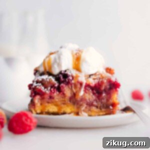 A beautifully presented slice of raspberry bread pudding on a pristine white plate, garnished with fresh raspberries and mint, ready to be enjoyed.