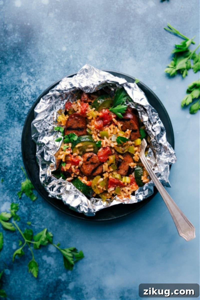 Tin Foil Jambalaya: A modern, convenient twist on a classic, featuring savory Cajun andouille sausage, vibrant vegetables, and perfectly cooked rice, all expertly prepared in a simple foil packet. Delicious Tin Foil Jambalaya, hot and ready to eat, served directly from the foil packet, highlighting the colorful ingredients like sausage, rice, and vegetables infused with rich Cajun spices.