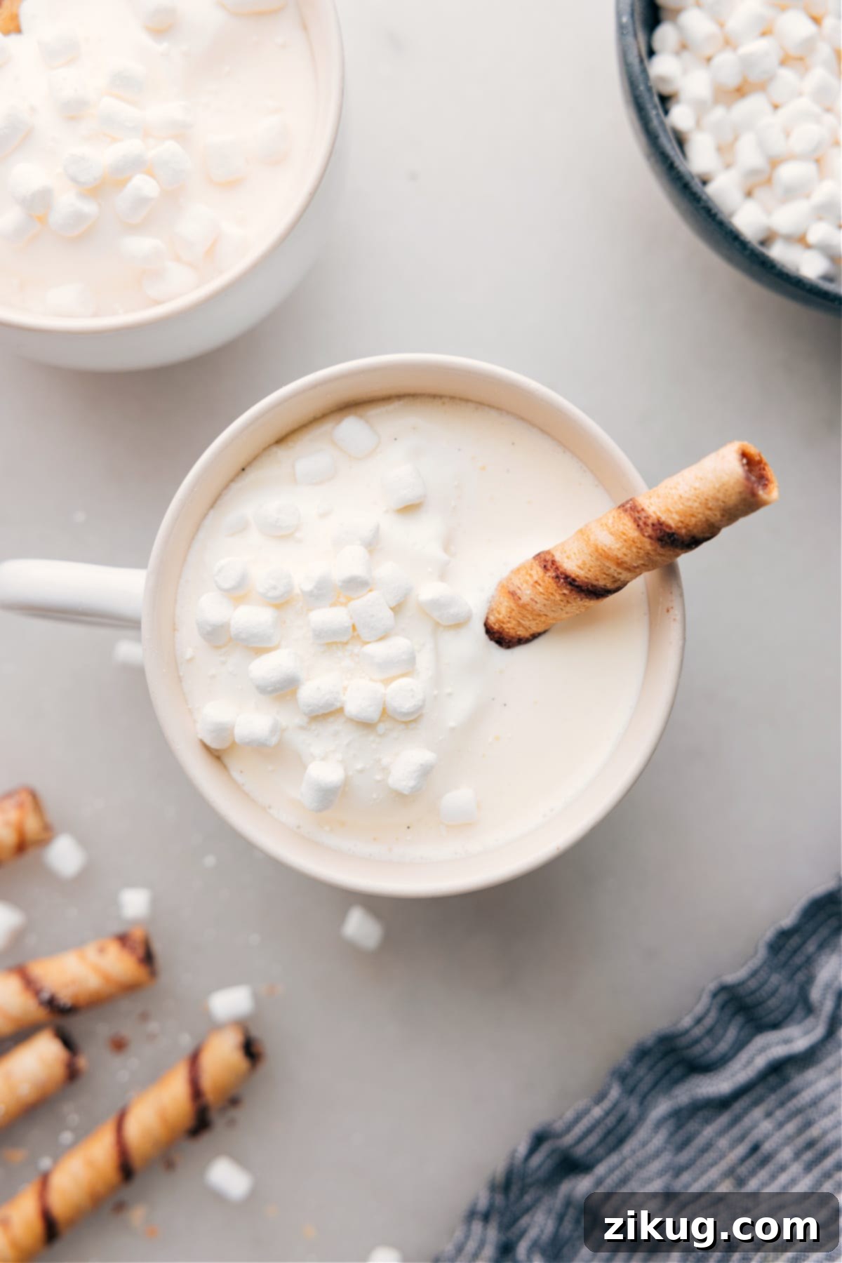 A mug of warm and delicious White Hot Chocolate, with fluffy marshmallows floating on top and a chocolate straw. The image evokes a cozy, tempting atmosphere, perfect for a chilly day.
