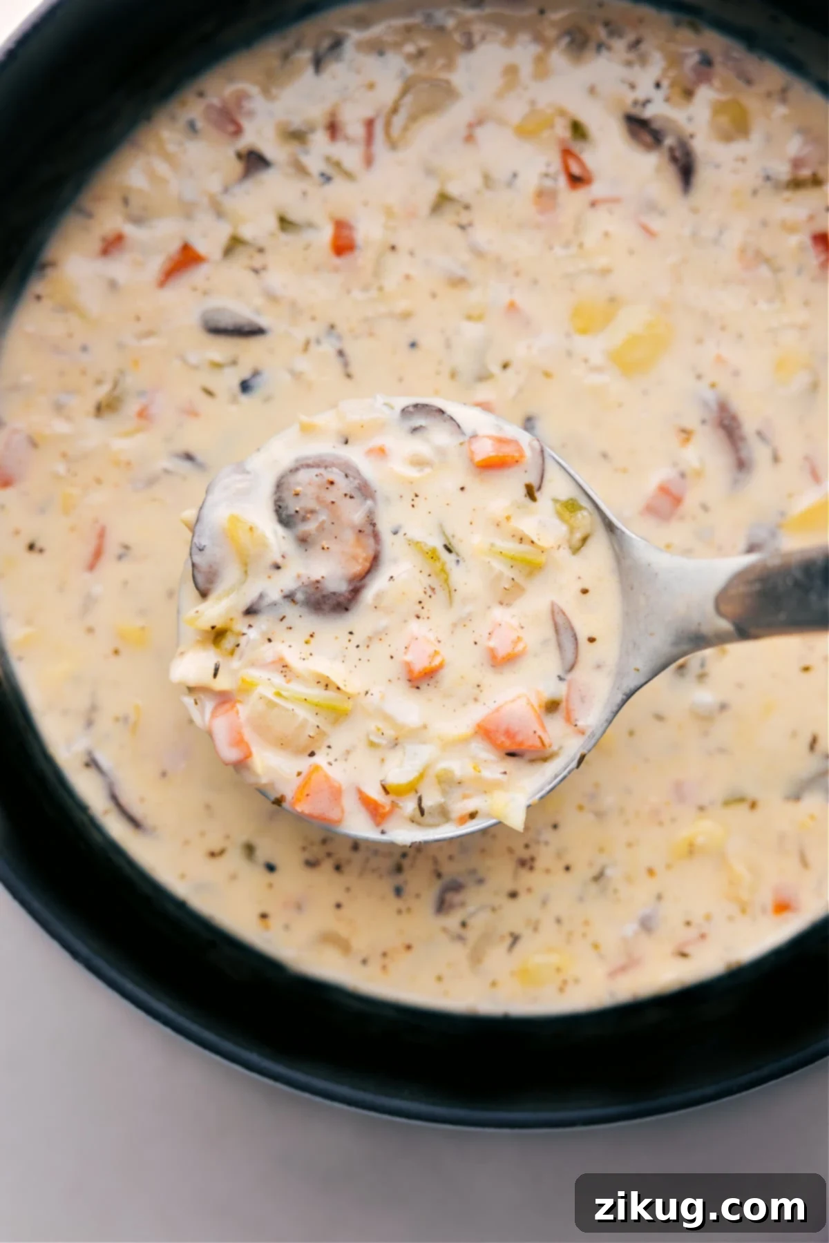 Creamy and rich artichoke soup, with a wooden ladle scooping out a steaming serving ready to be enjoyed. The soup is golden brown, topped with fresh herbs, in a rustic bowl on a wooden surface.