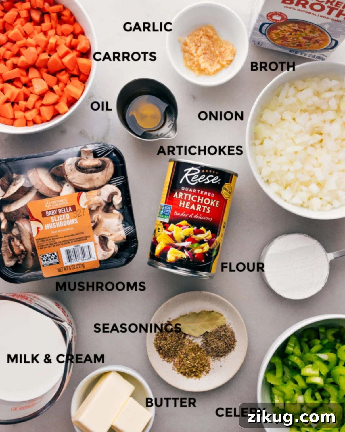 Assortment of fresh and canned ingredients for the creamy artichoke soup recipe, including mushrooms, butter, onion, milk, cream, garlic, broth, and artichoke hearts arranged on a wooden board.