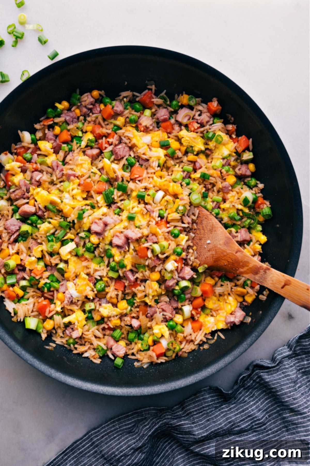 The Best Ham Fried Rice A large pot of golden-brown Ham Fried Rice garnished with green onions, ready to be served and enjoyed by family and friends.