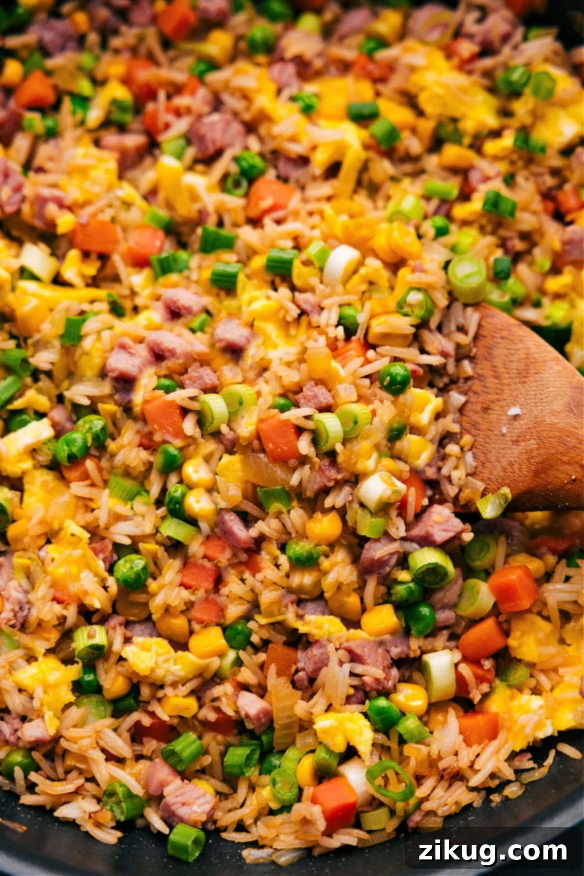 Everyones Favorite Ham Fried Rice A close-up shot of a spoon filled with delicious Ham Fried Rice, garnished with green onions, perfectly cooked and ready to be savored.