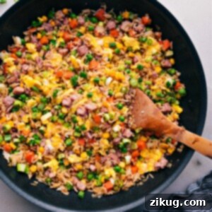 Classic Ham Fried Rice 2 A delightful close-up of a large pot brimming with golden-brown Ham Fried Rice, generously garnished with fresh green onions, showcasing its appetizing texture and vibrant colors.