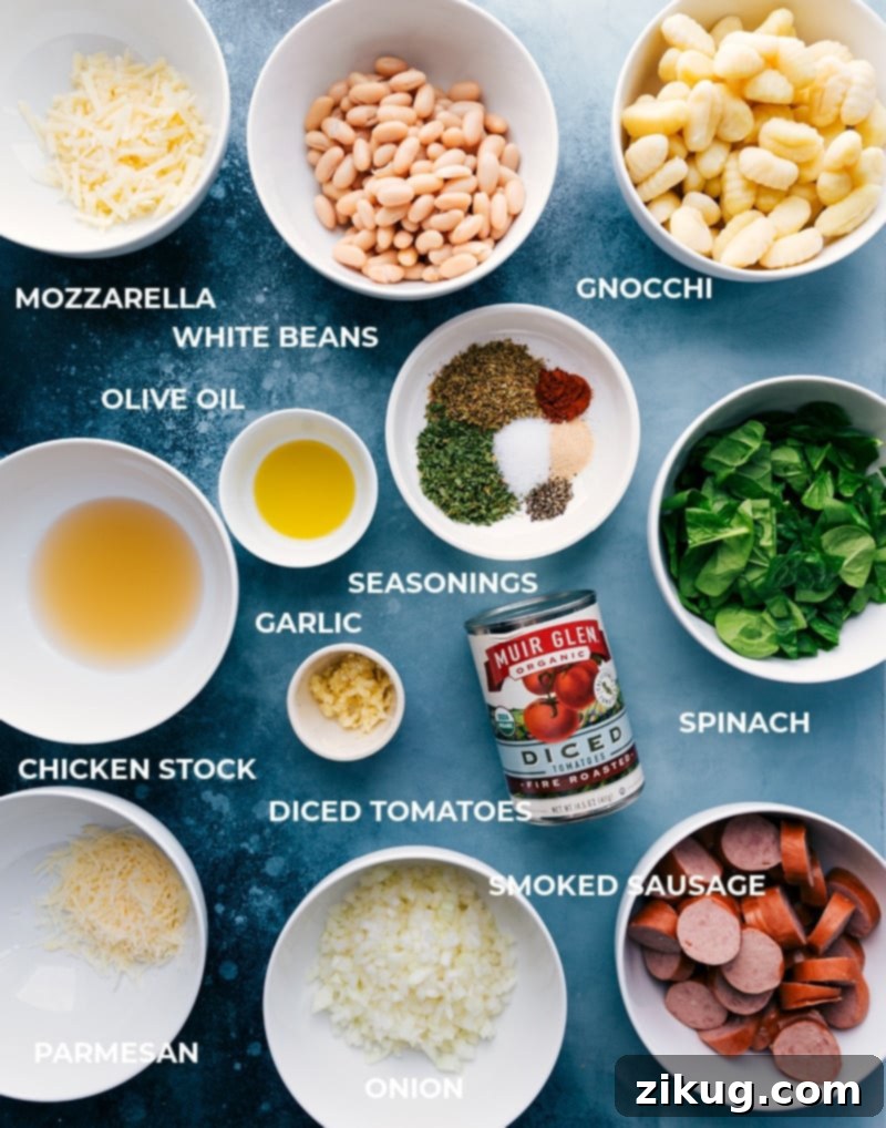 This White Bean Gnocchi combines aromatics, smoked sausage, savory white beans, tender gnocchi, fire-roasted tomatoes, and baby spinach for an explosion of flavor and textures! This nutritious and hearty meal can be prepared in less than 30 minutes and is made in one skillet! Recipe via chelseasmessyapron #dinner #comfort #comfortfood #best #delicious #easy #simple #onepan #whitebean #gnocchi Individual ingredients laid out for making White Bean Gnocchi, including gnocchi, sausage, tomatoes, spinach, and spices.