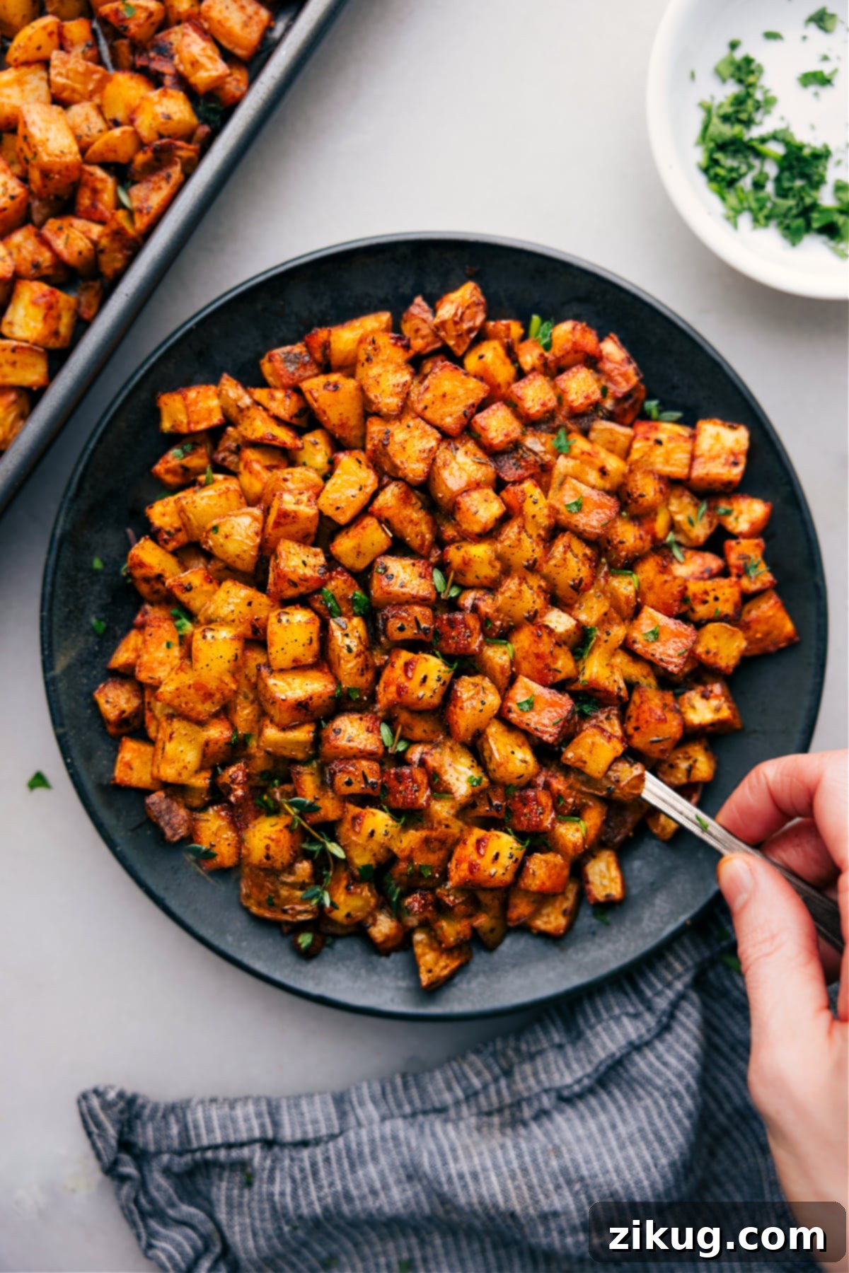 A large plate overflowing with perfectly cooked and seasoned breakfast potatoes, ready to be devoured.