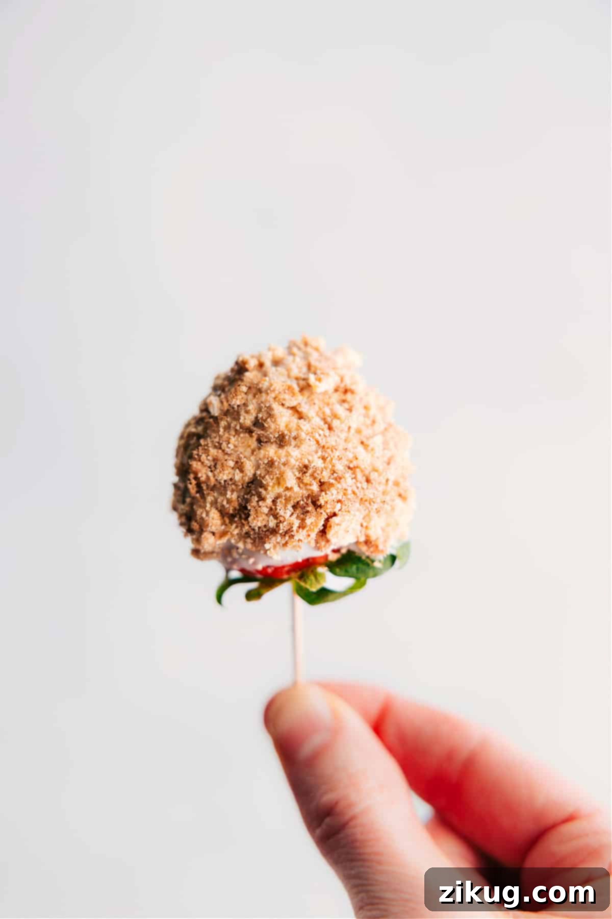 Our Favorite Chocolate Dipped Strawberries: A sweet and crunchy delight. A close-up view of a perfectly dipped strawberry, showcasing a smooth white chocolate coating generously sprinkled with crunchy graham cracker crumbs, ready to be enjoyed.