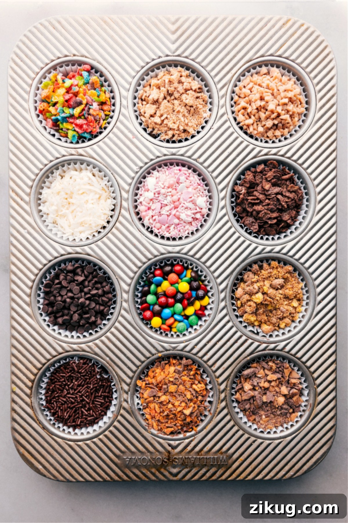 Chocolate-Covered Strawberry Dessert Bar: A delightful assortment of toppings. A muffin pan neatly organized with various colorful and tempting toppings for a Chocolate-Covered Strawberry Dessert Bar, showcasing a vibrant array of choices for customization.