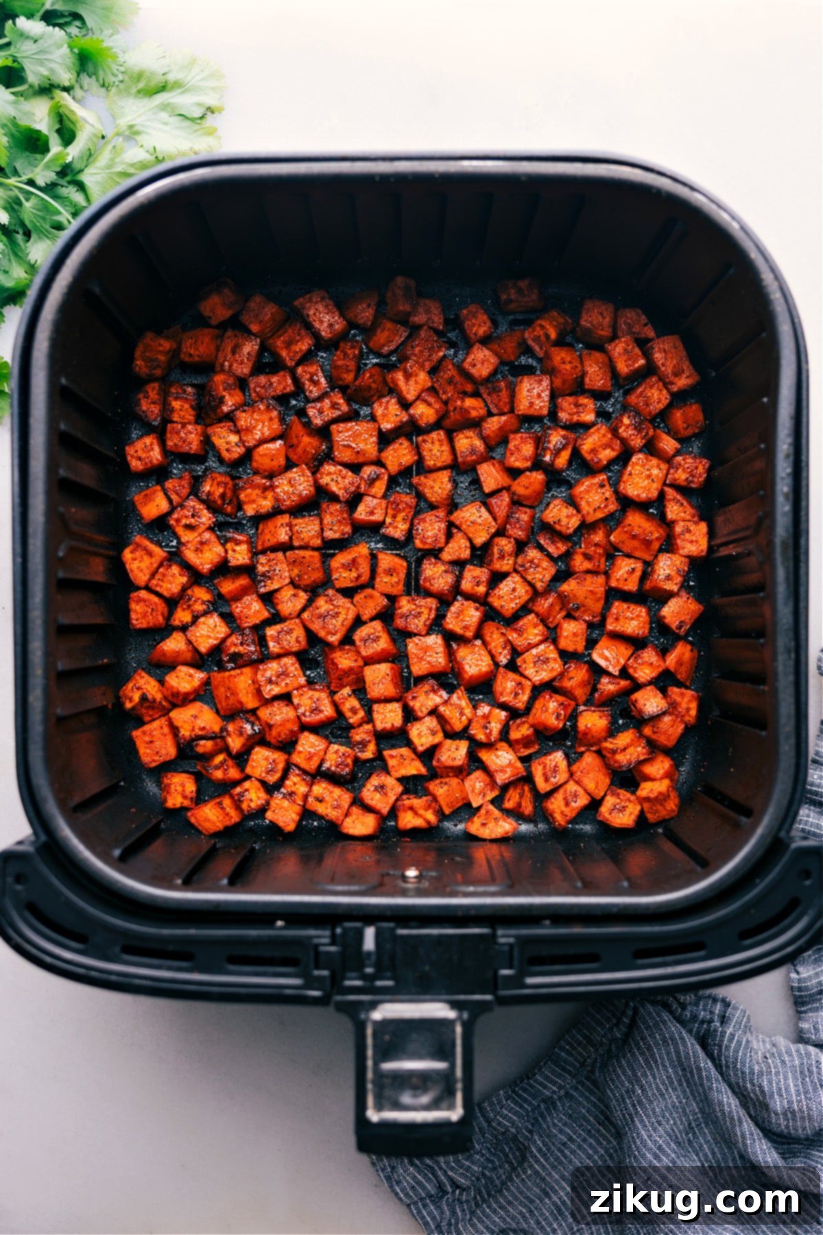 Air Fryer Sweet Potatoes, fresh out of the air fryer and perfectly cooked. Close-up photo of perfectly air-fried sweet potato cubes in a basket, golden brown and crispy.
