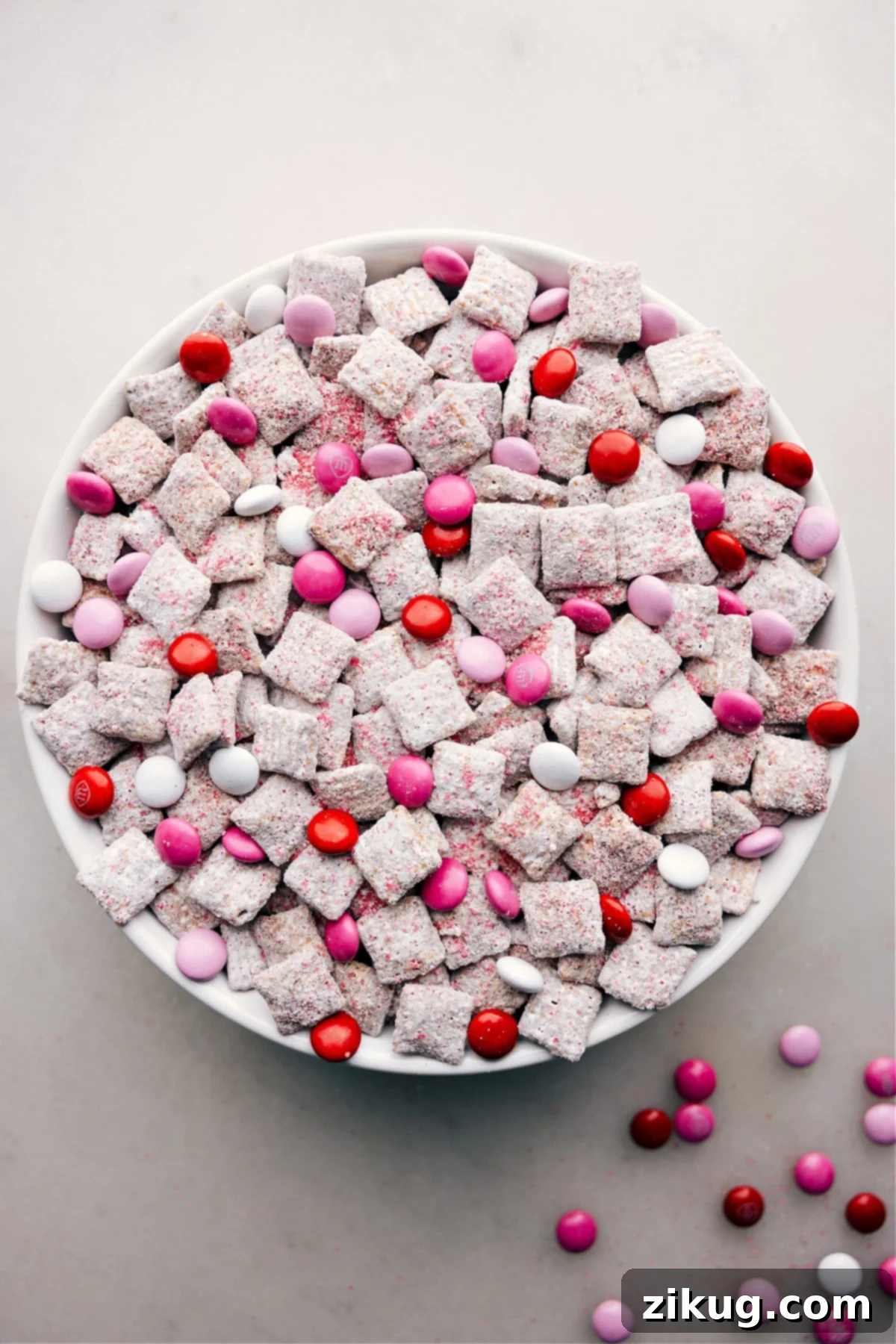 Irresistible Valentine Muddy Buddies Snack Mix A large bowl filled with festive Valentine Muddy Buddies, showcasing the colorful M&Ms and powdered sugar coating, ready to be enjoyed.