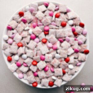 A large bowl of Valentine Muddy Buddies, colorful and ready to serve, speckled with festive M&Ms.
