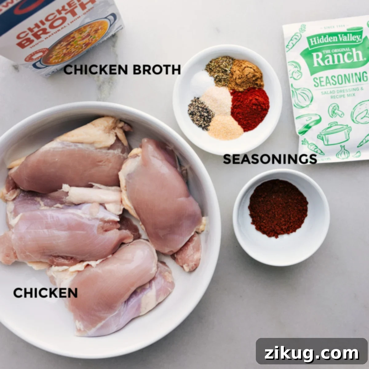 A flat lay image displaying all the essential ingredients for Crockpot Shredded Chicken Tacos, including chicken thighs, various seasonings, and chicken broth, neatly arranged for easy preparation.