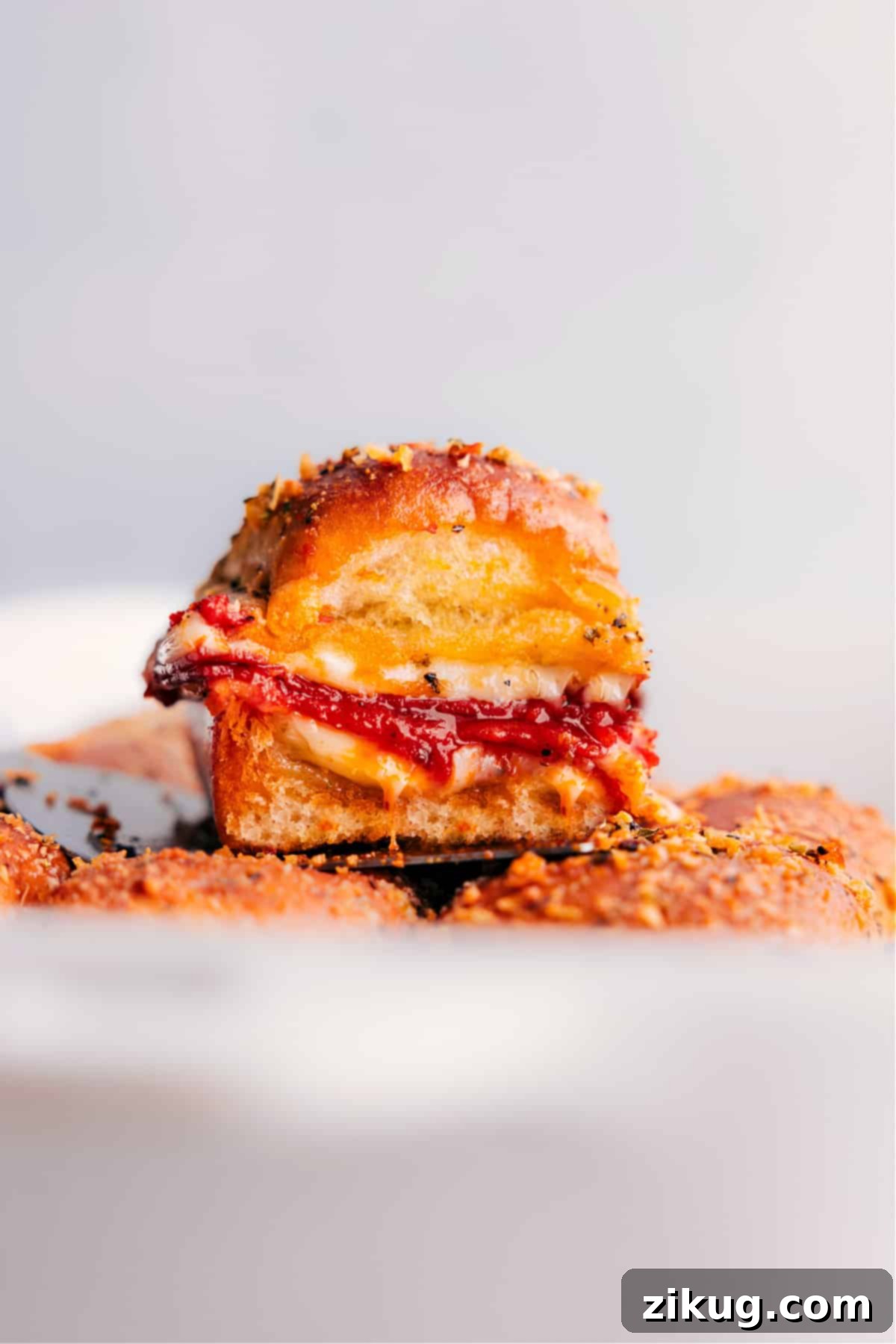 Golden-brown Pizza Sliders fresh out of the oven, nestled in a baking pan, oozing with melted cheese and pepperoni.
