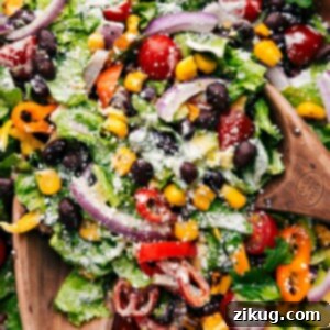 Mexican Salad being tossed with the dressing in a large bowl, showcasing its vibrant colors.