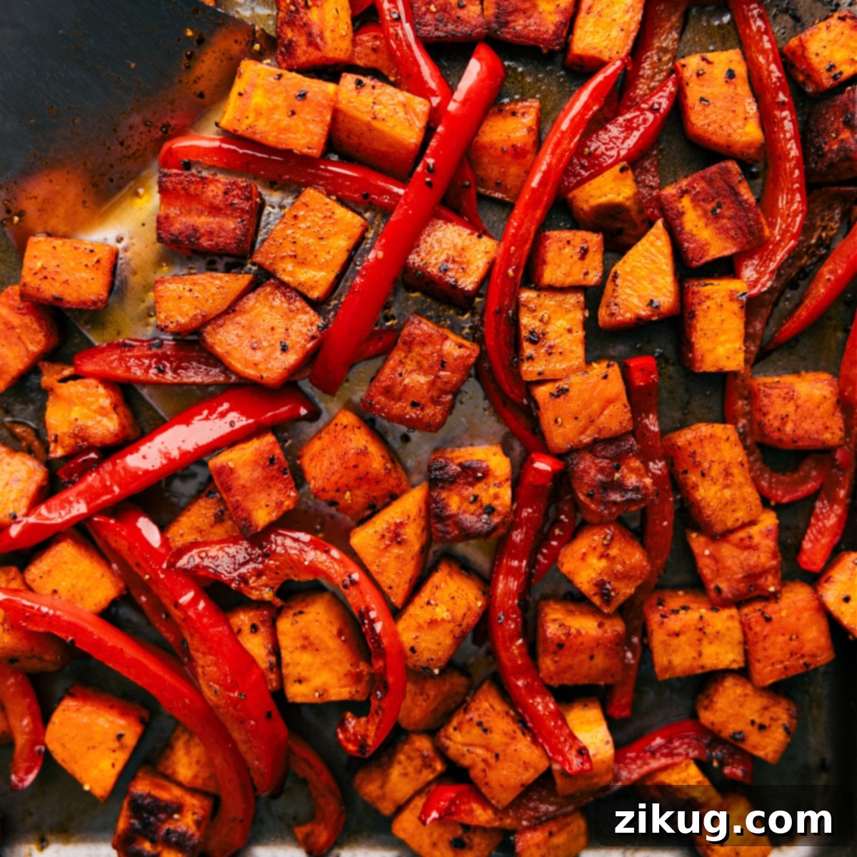 Freshly roasted potatoes and peppers: Golden and Delicious A baking sheet filled with freshly roasted sweet potatoes and red bell peppers, glistening golden brown and slightly caramelized from the oven, ready to be added to the burrito bowls.