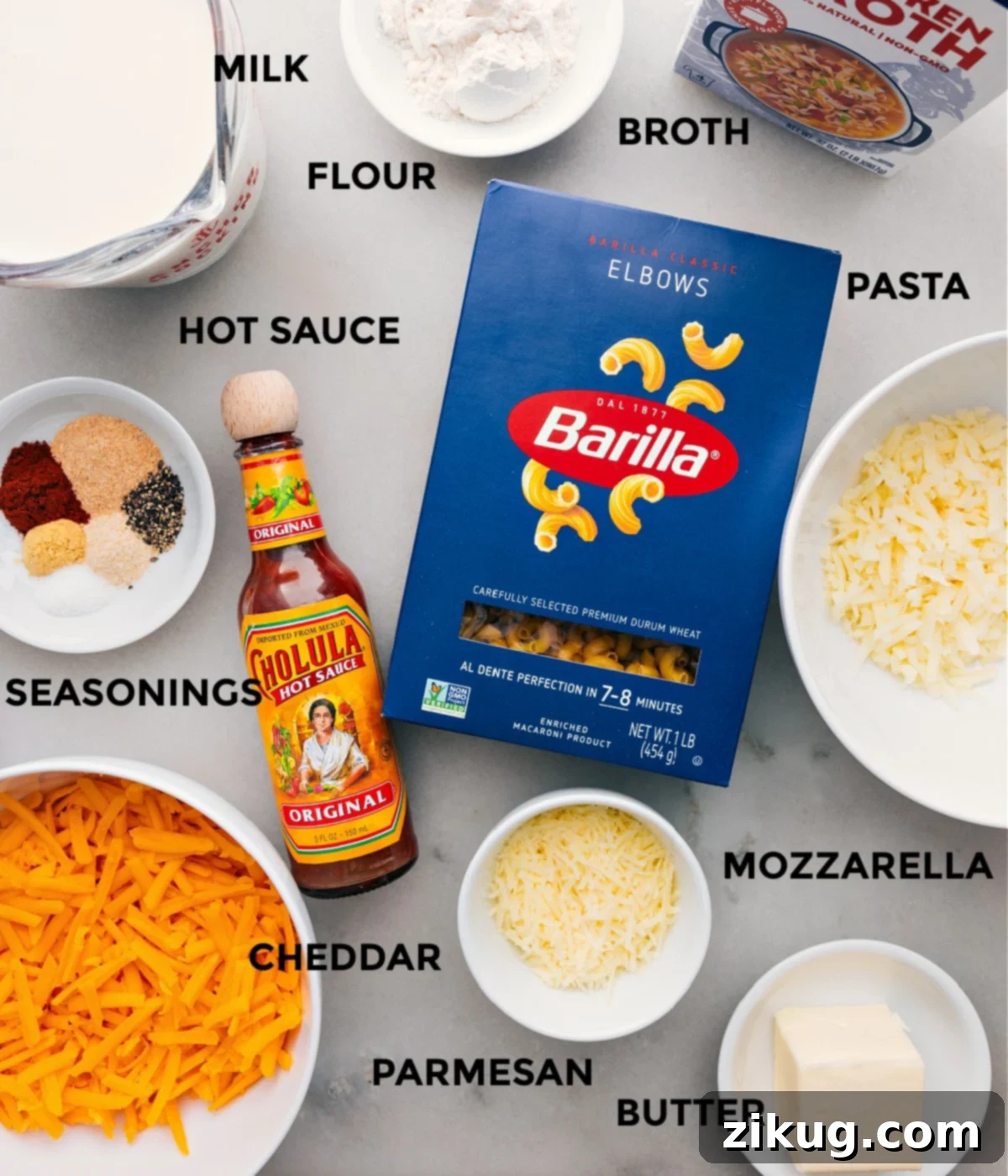 Essential Mac And Cheese Ingredients Various mac and cheese ingredients meticulously prepped and laid out on a kitchen counter, including blocks of cheese, milk, macaroni, butter, and spices, ready for easy assembly.