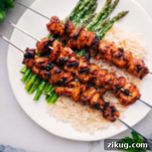 Baked Chicken Bites on skewers over rice and asparagus.