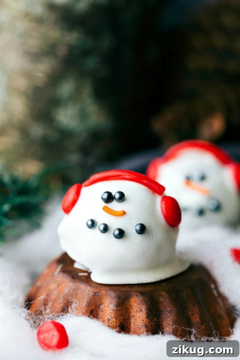 Festive OREO Truffle Delights 8 Image of a cheerful snowman Oreo truffle, complete with a white chocolate coating, black sprinkle eyes, an orange carrot nose, and red licorice earmuffs, ready for the holidays.