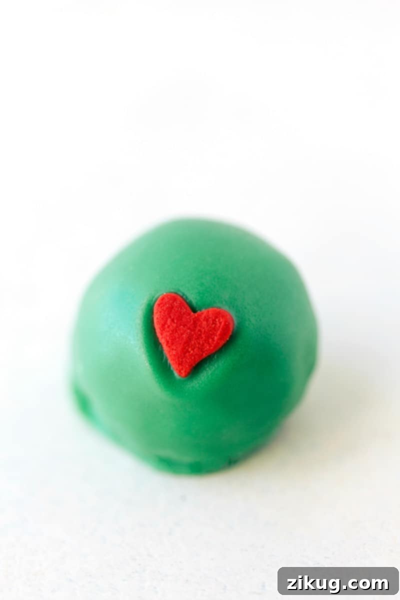 Festive OREO Truffle Delights 10 Image of a Grinch-themed Christmas heart Oreo truffle, beautifully coated in vibrant green with a prominent red heart decoration, symbolizing holiday affection.