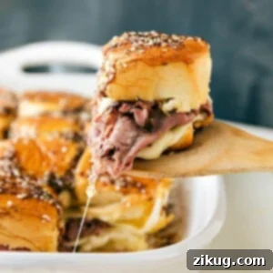 French Dip sandwiches fresh out of the oven with a spatula pulling one out.
