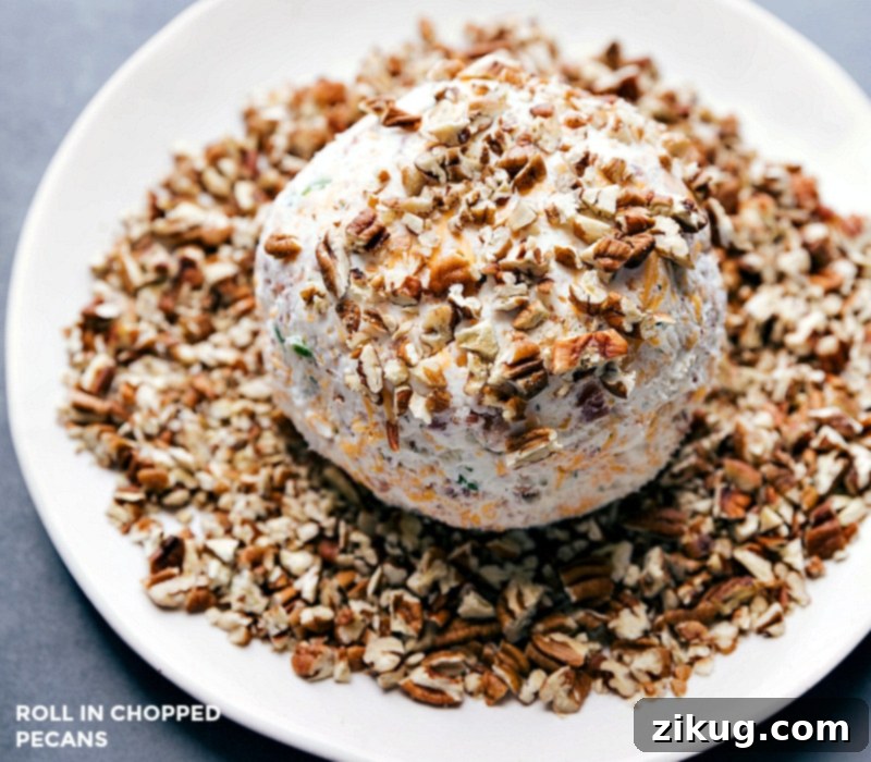 Rolling the Savory Cheese Ball in Chopped Pecans for a Beautiful Finish Rolling the cheese ball in finely chopped pecans to make the already delicious snack even more beautiful and add a textural crunch.