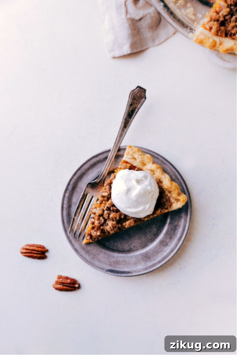 The Best Pumpkin Pecan Pie Slice with Maple Whipped Cream A delectable slice of Pumpkin Pecan Pie topped with a generous swirl of maple whipped cream, ready to be enjoyed.