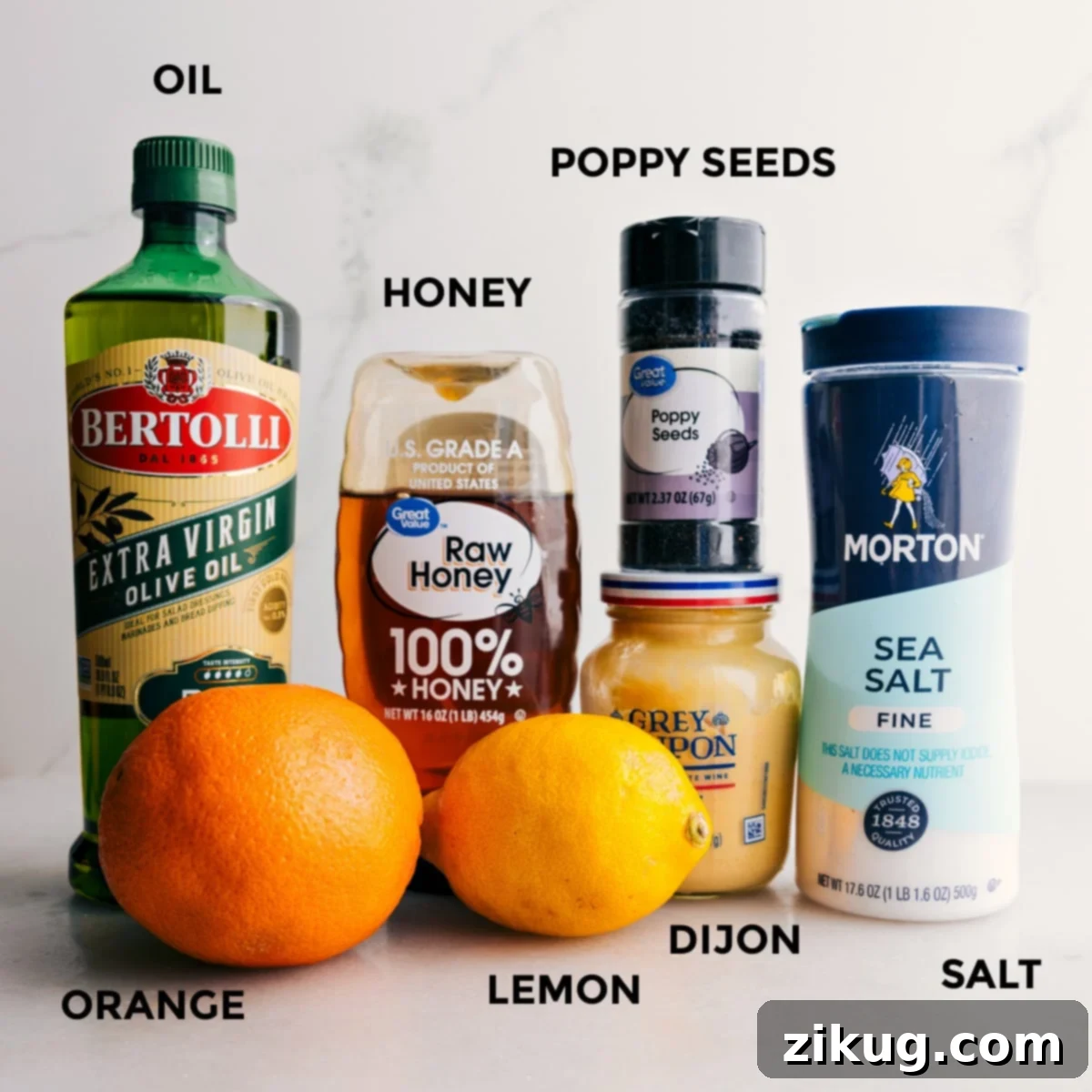 A selection of fresh ingredients prepared for the mandarin orange salad dressing, including olive oil, honey, poppy seeds, salt, Dijon mustard, and sliced lemons and oranges.