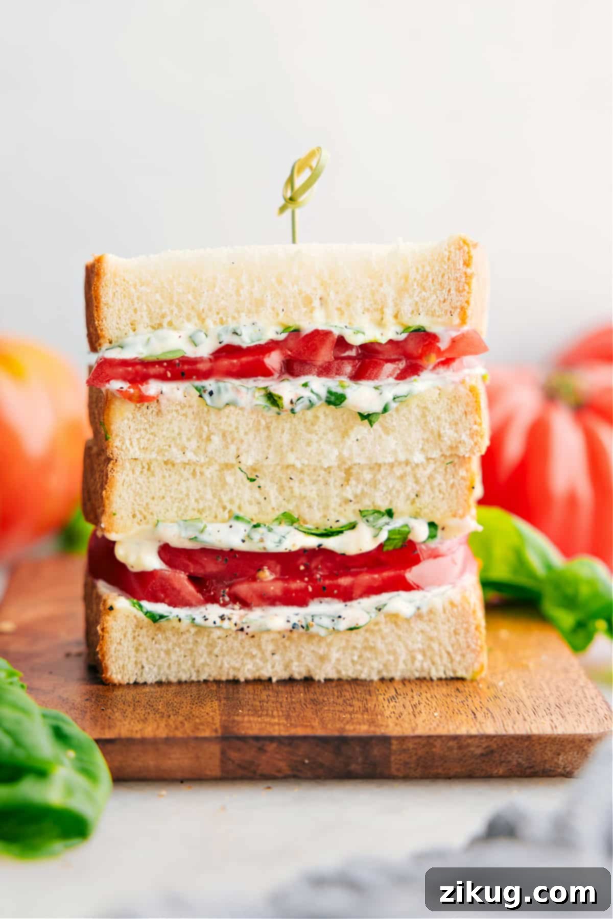 Stacked tomato sandwiches showcasing juicy tomato slices and creamy basil mayo.