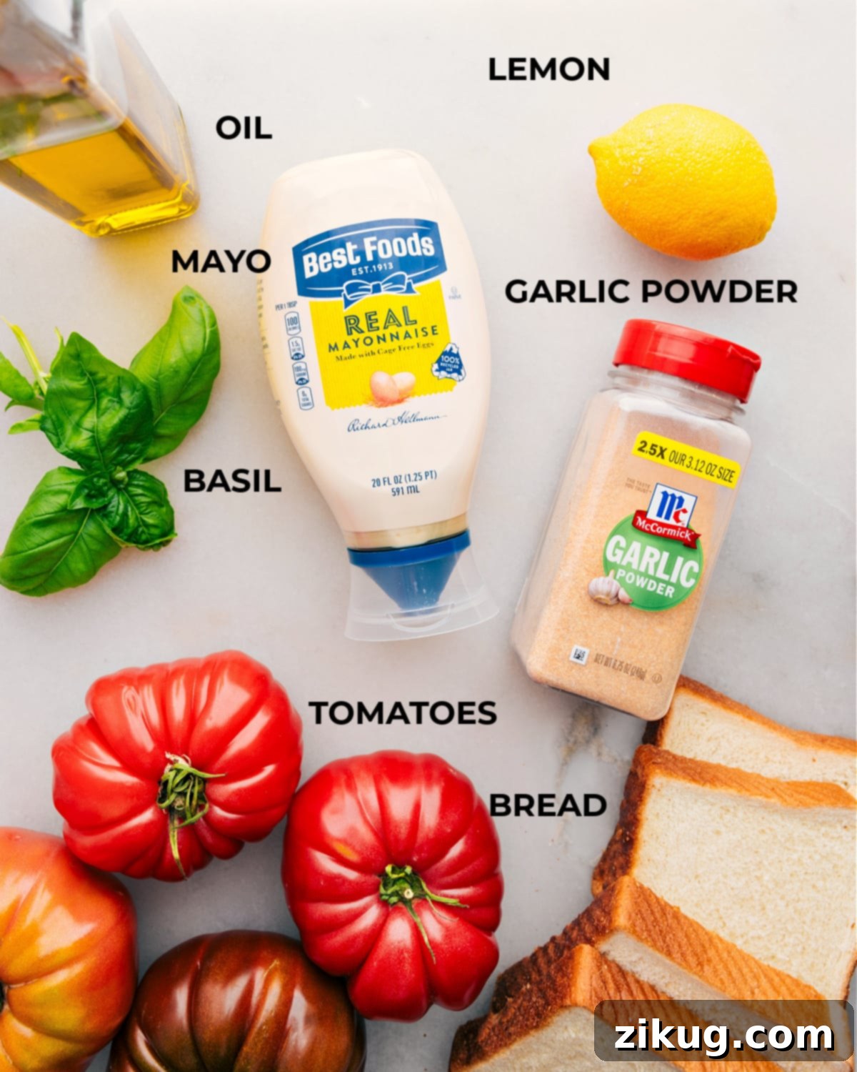 All fresh ingredients for a tomato sandwich, neatly prepped and laid out on a cutting board.