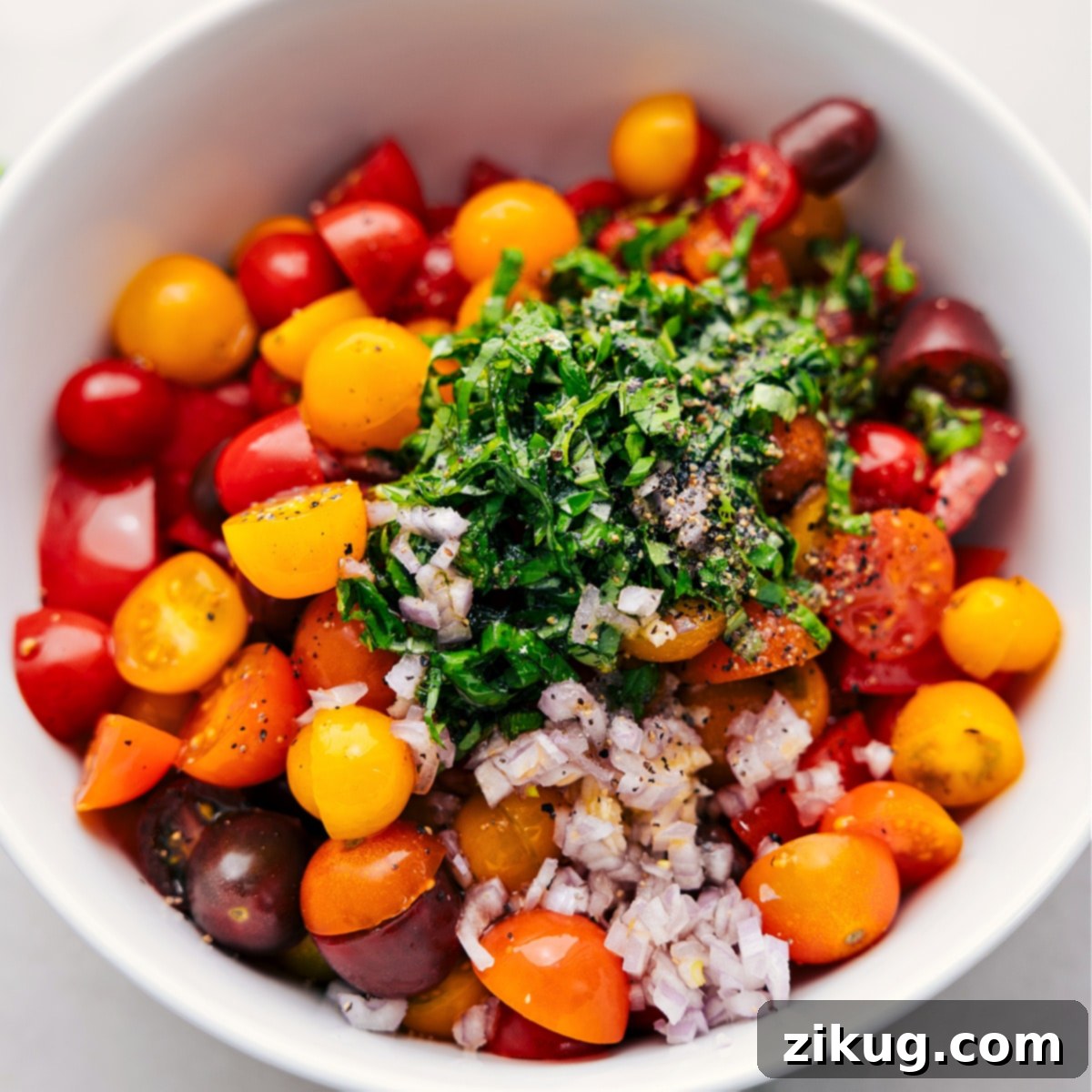A large bowl filled with all the chopped tomato salad ingredients, ready to be tossed with dressing.