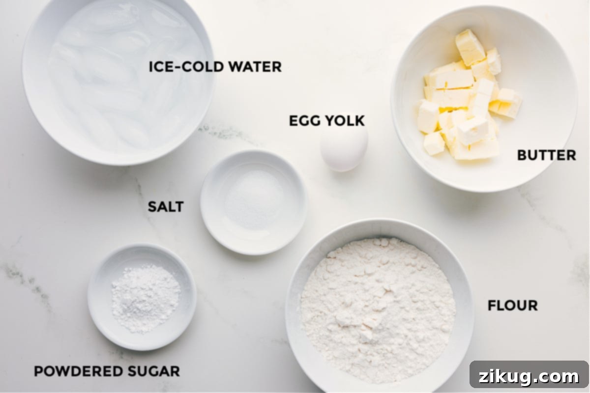 All the essential ingredients prepped and ready: flour, cold butter cubes, an egg yolk, salt, powdered sugar, and a glass of ice-cold water, crucial for easy assembly and a perfect pie crust.