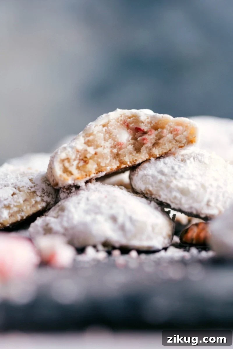 Peppermint Snowball Cookies Stacked with a Bite Revealing Moist and Flavor-Packed Interior Delicious and seasonal desserts stacked on top of each other, with a bite out of one revealing the moist and flavor-packed interior.