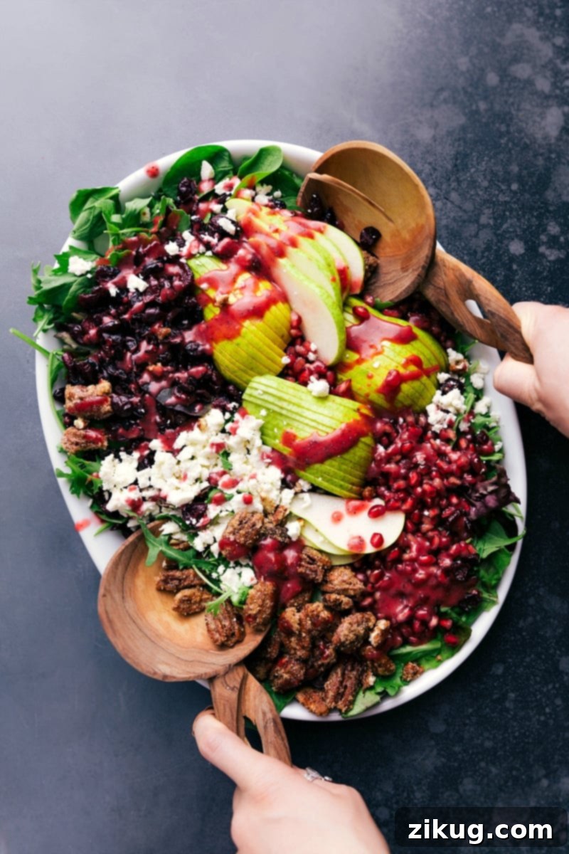 Gourmet Pear Pomegranate Salad: A Symphony of Fresh Flavors A vibrant bowl of Pear Pomegranate Salad, richly packed with fresh mixed greens, golden candied pecans, juicy pear slices, ruby red pomegranate arils, and a glistening drizzle of raspberry poppy seed dressing.
