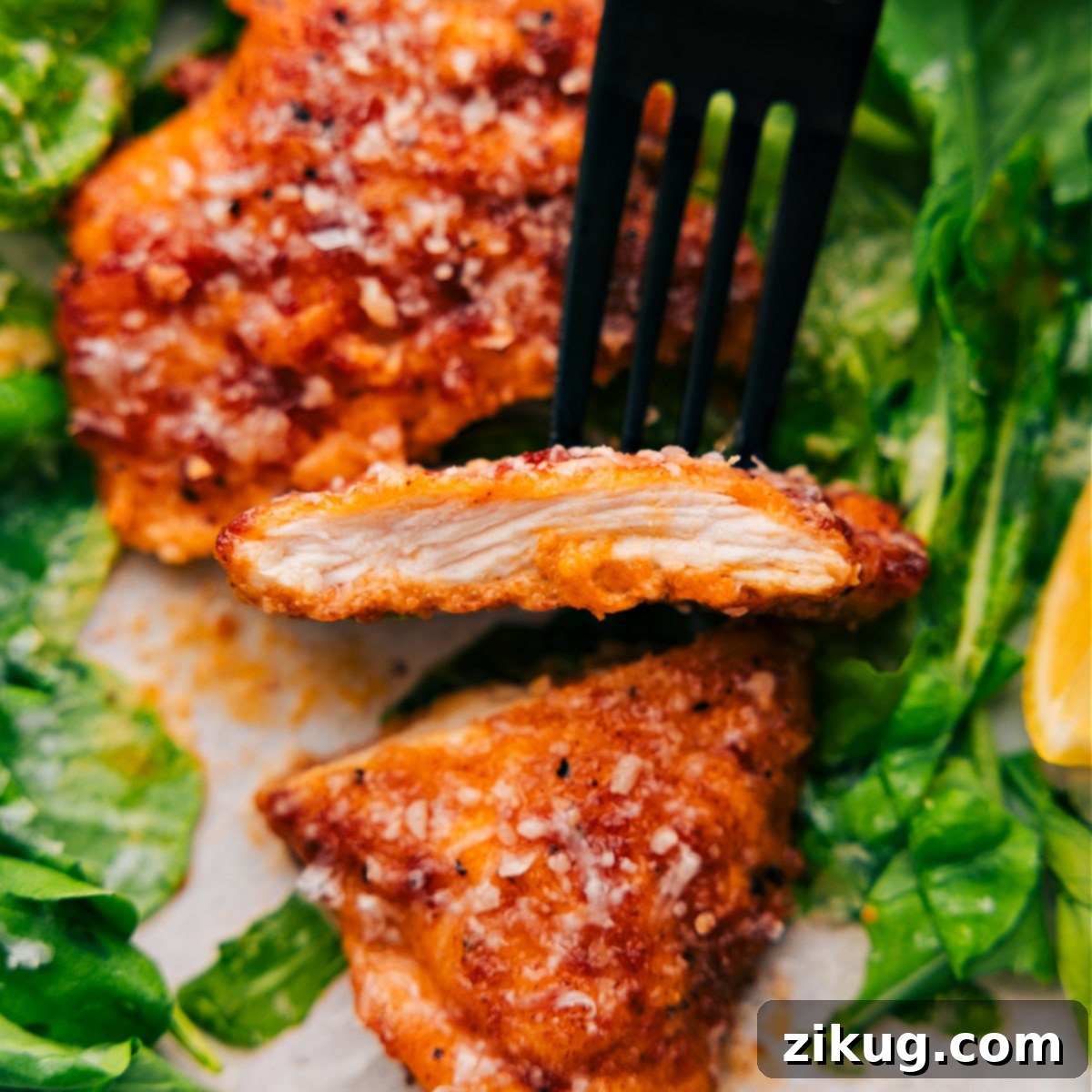 A perfectly cooked chicken cutlet is sliced, revealing its tender and juicy interior, held up with a serving fork, ready to be enjoyed as part of a delicious weeknight dinner.