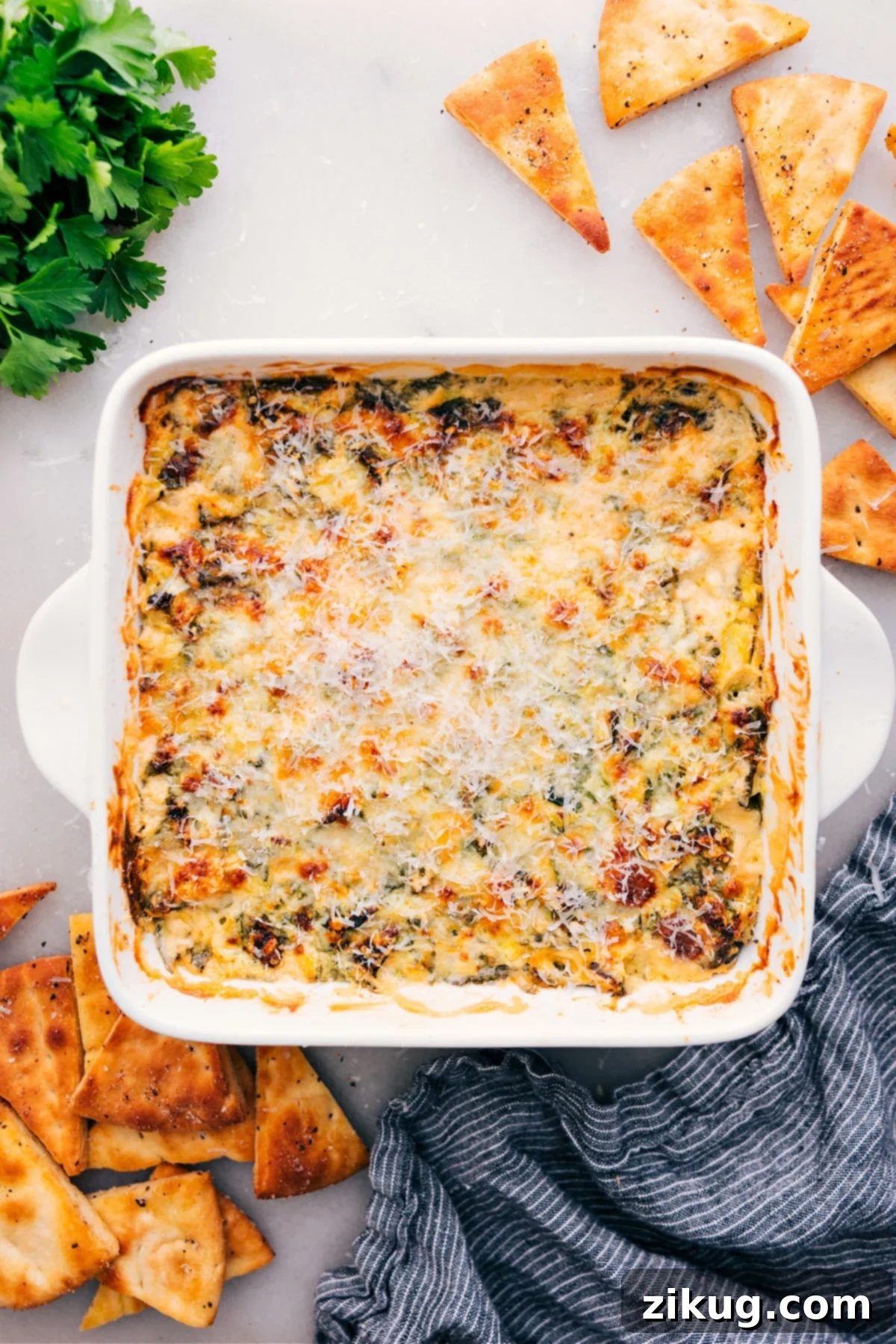 The Ultimate Party Dip: Spinach Artichoke Dip The ultimate party appetizer, a golden-brown and bubbling Spinach Artichoke Dip, fresh out of the oven and surrounded by various dippers, ready to be enjoyed by eager guests.