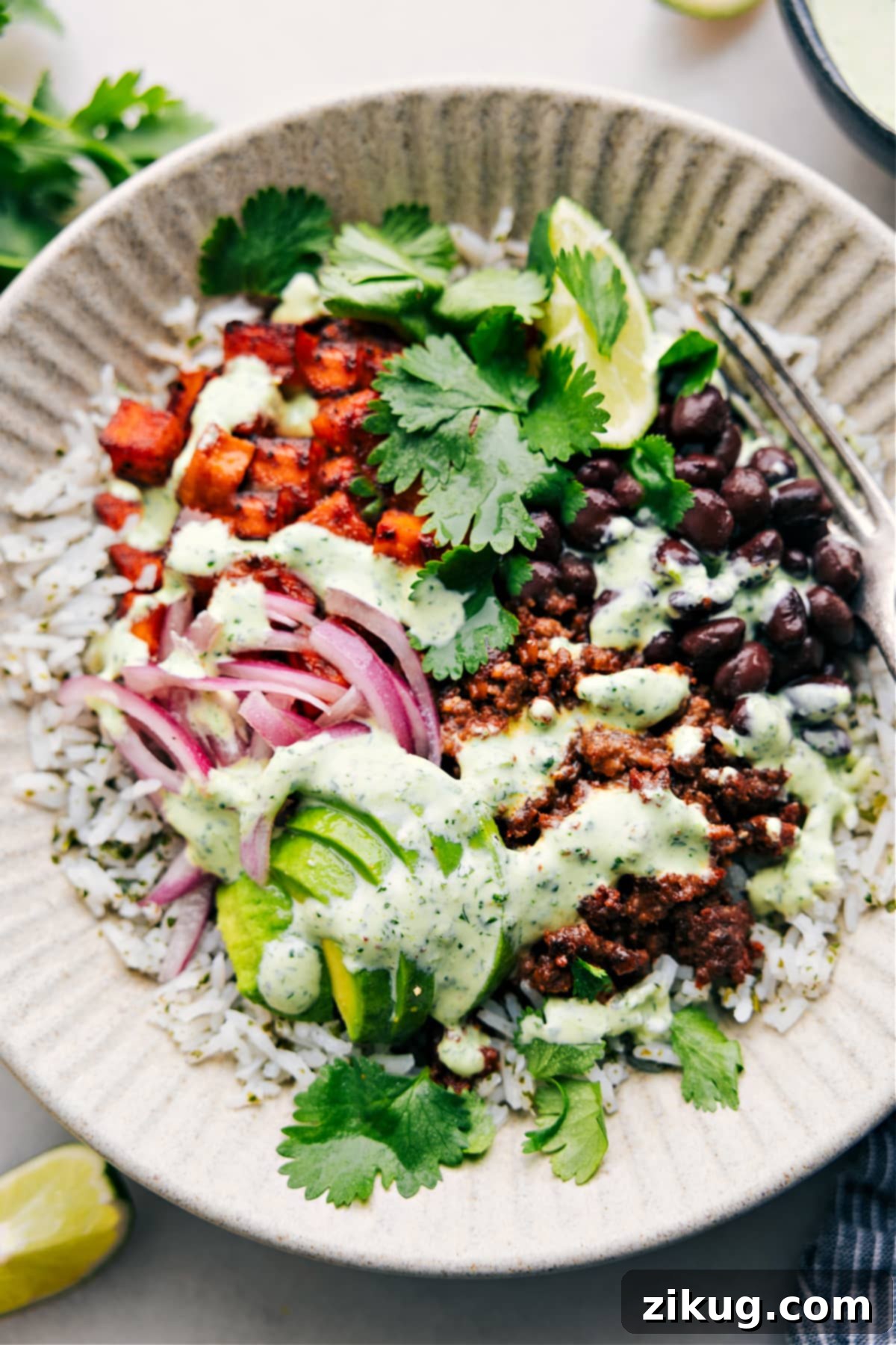 A perfectly assembled Beef Burrito Bowl, generously drizzled with creamy cilantro lime sauce, ready for a satisfying dinner.