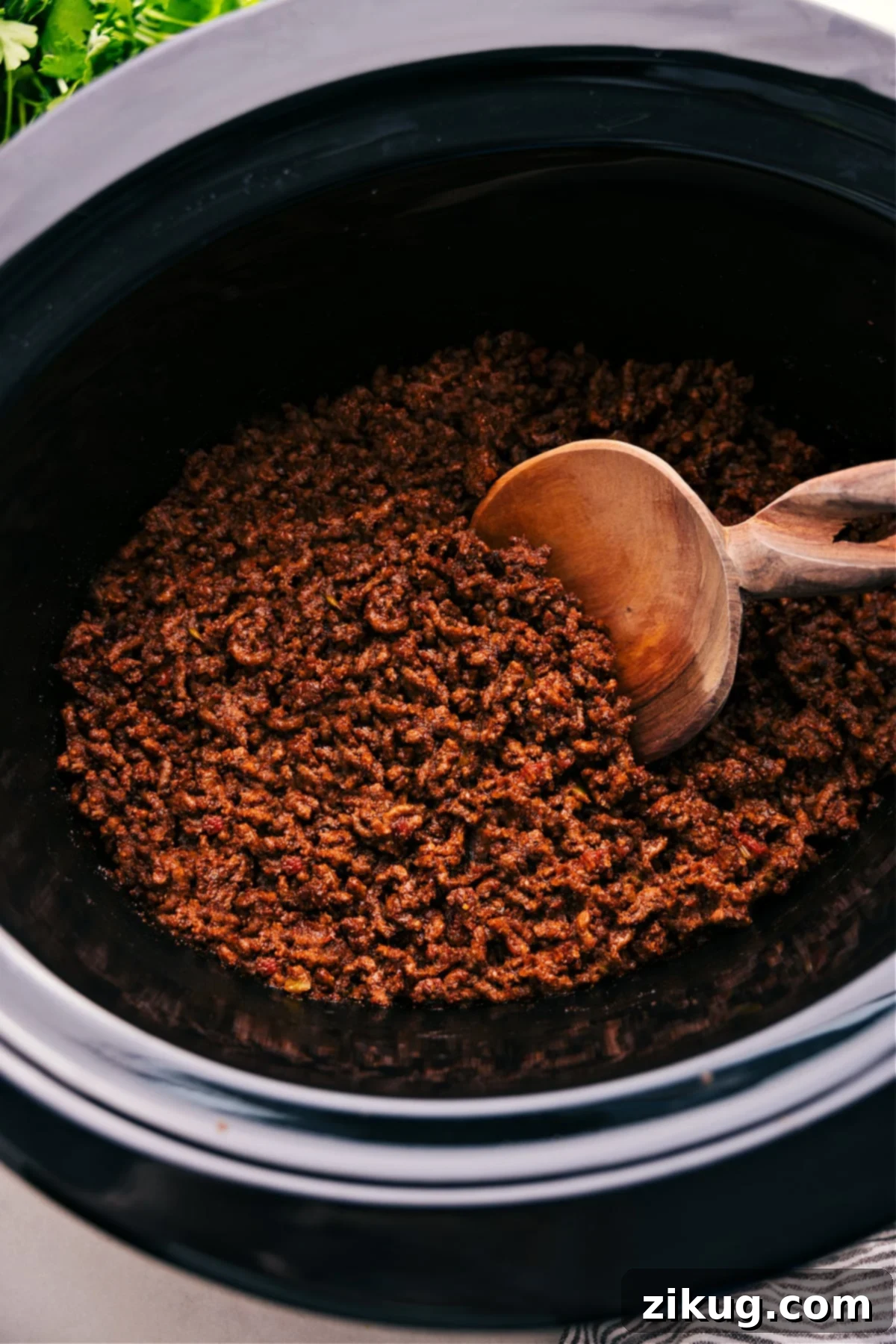 The Best Crockpot Taco Meat Crockpot Taco Meat simmering in a slow cooker, with a spoon lifting a portion.