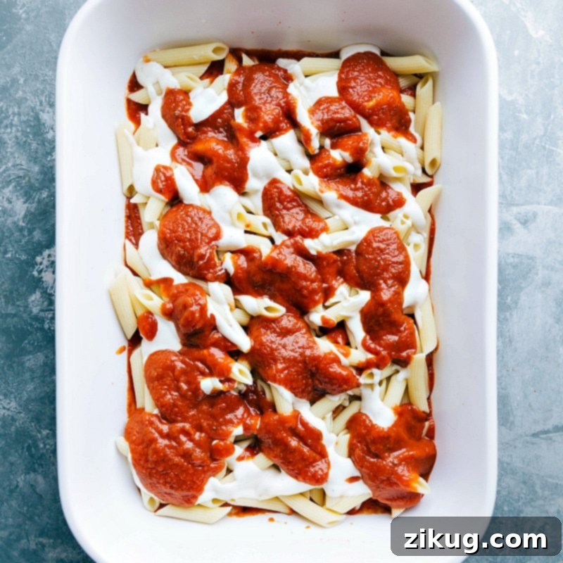 Crimson and Cream Pasta 3 Marinara sauce being layered on top of alfredo sauce in a pasta dish, creating a rich flavor combination.