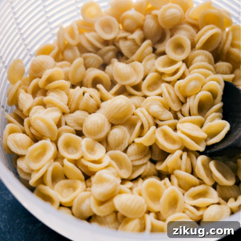 A close-up process shot of perfectly cooked orecchiette pasta, drained and ready to be tossed with the flavorful broccoli and sausage sauce.