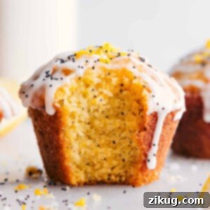 Lemon poppy seed muffin with a fresh bite mark, revealing its moist interior, and adorned with creamy frosting.