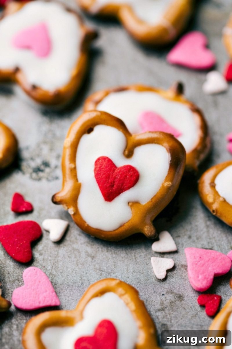 Sweet & Simple: 4 Valentine's Day Delights 7 Several White Chocolate Heart Pretzels arranged on a light surface. Each mini pretzel twist is filled with creamy white chocolate and adorned with a single jumbo heart sprinkle in the center, creating a simple yet elegant Valentine's Day confection.