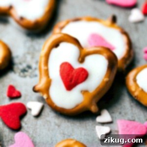 Sweet & Simple: 4 Valentine's Day Delights 8 Close-up of a White Chocolate Heart Pretzel featuring a mini pretzel twist filled with smooth white chocolate and topped with a single red heart sprinkle. The image highlights the clean, sweet details of this homemade Valentine's Day treat.