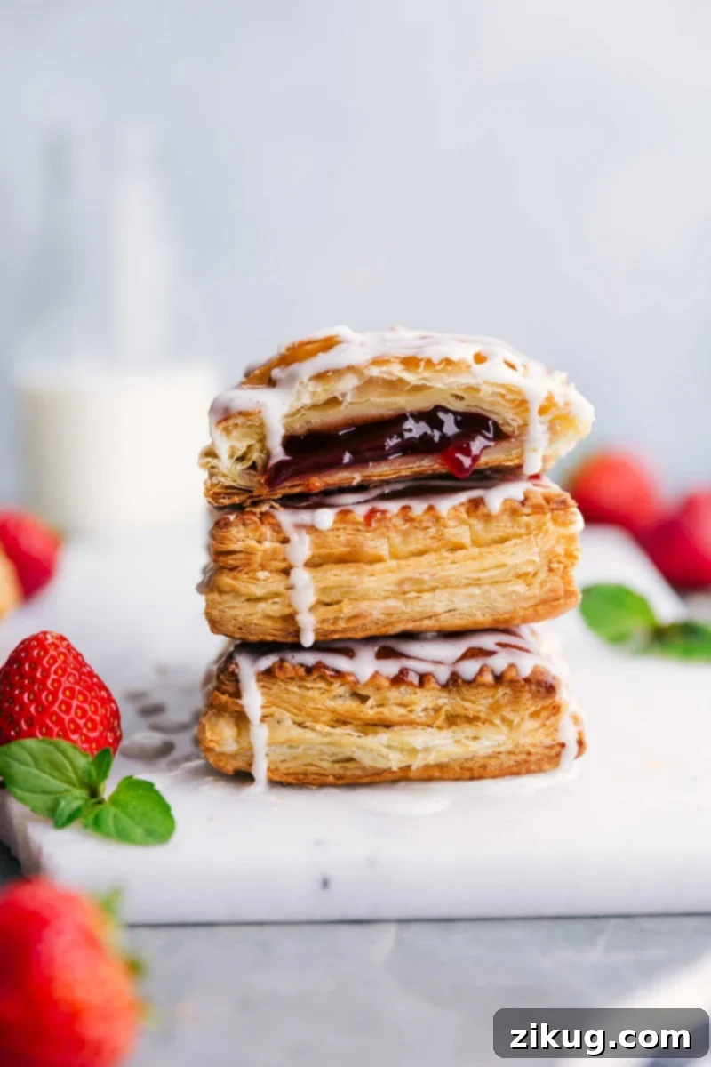Delectable Homemade Toaster Strudels Tower with Fresh Strawberries Stacked homemade Toaster Strudels glistening with vanilla glaze, accompanied by a scattering of fresh strawberries.