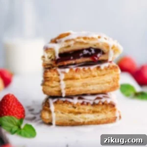 Stacked homemade Toaster Strudels with a side of fresh strawberries, perfectly glazed and ready to eat.