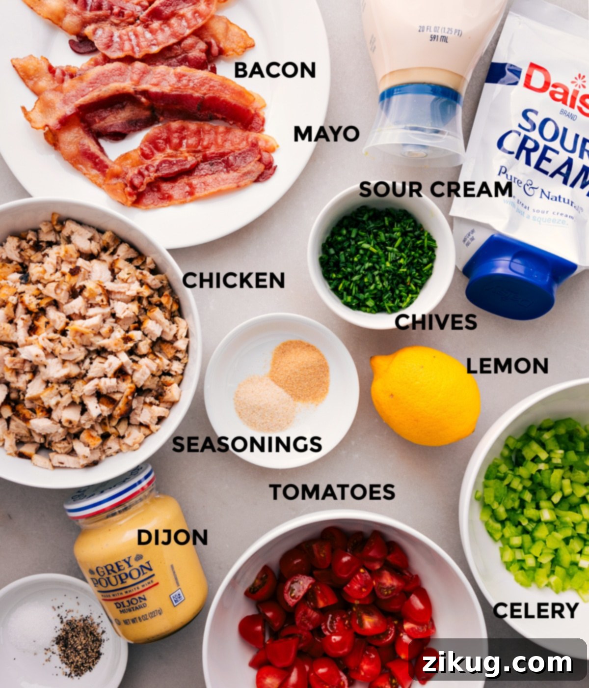 All the ingredients for this recipe are prepped and ready for easy assembly, including the meat, mayo, sour cream, chives, seasonings, lemon, celery, tomatoes, and Dijon.